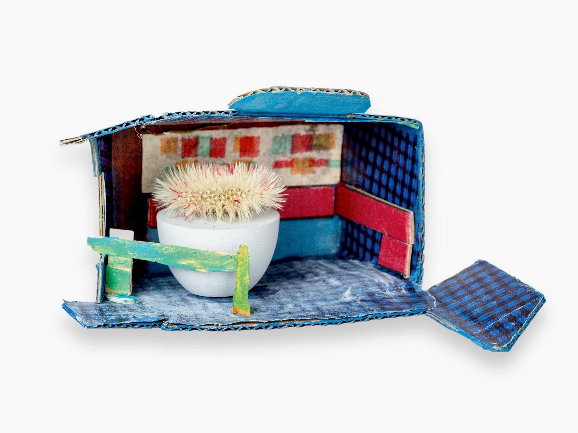 Kleine, farbenfrohe Modellszene aus Pappe mit einem weißen Blumentopf und einem Kaktus darin, gestaltet wie ein Miniaturraum.