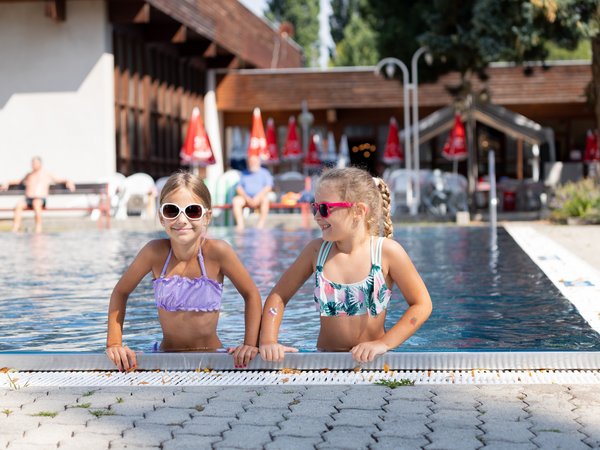 Zwei Mädchen mit Sonnenbrillen am Beckenrand des Kremser Freibades