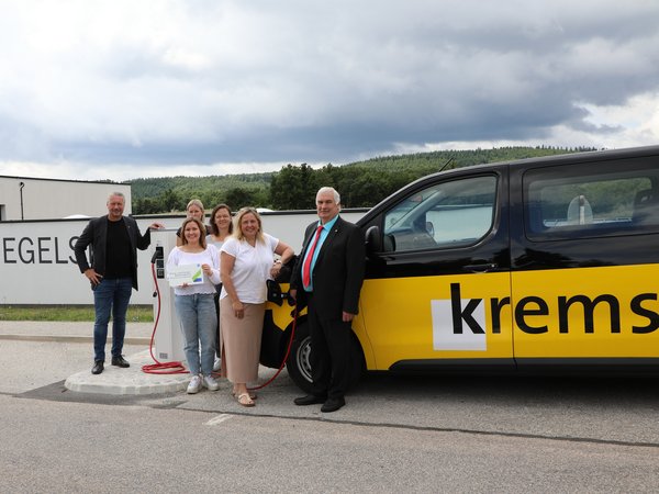 Gruppe vor der Feuerwache Egelsee neben einem Elektrofahrzeug der Stadt Krems.