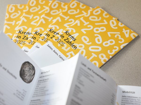 Mehrere Folder "Krems in Zahlen 2025 nebeneinander, ein aufgeklappter Folder im Vordergrund