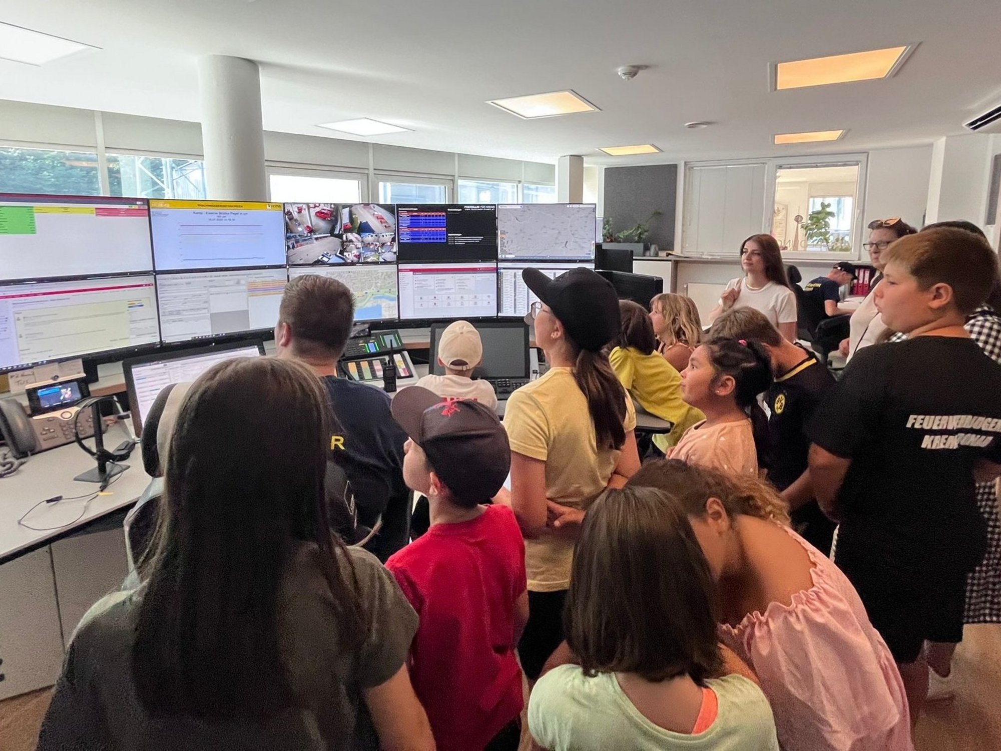 Kindergruppe in der Einsatzzentrale der Feuerwehr Krems vor mehreren Monitoren.
