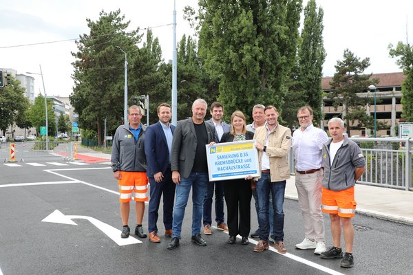 Männer und Frauen auf der Kremsbrücke bei der Fertigstellung der Sanierungsarbeiten