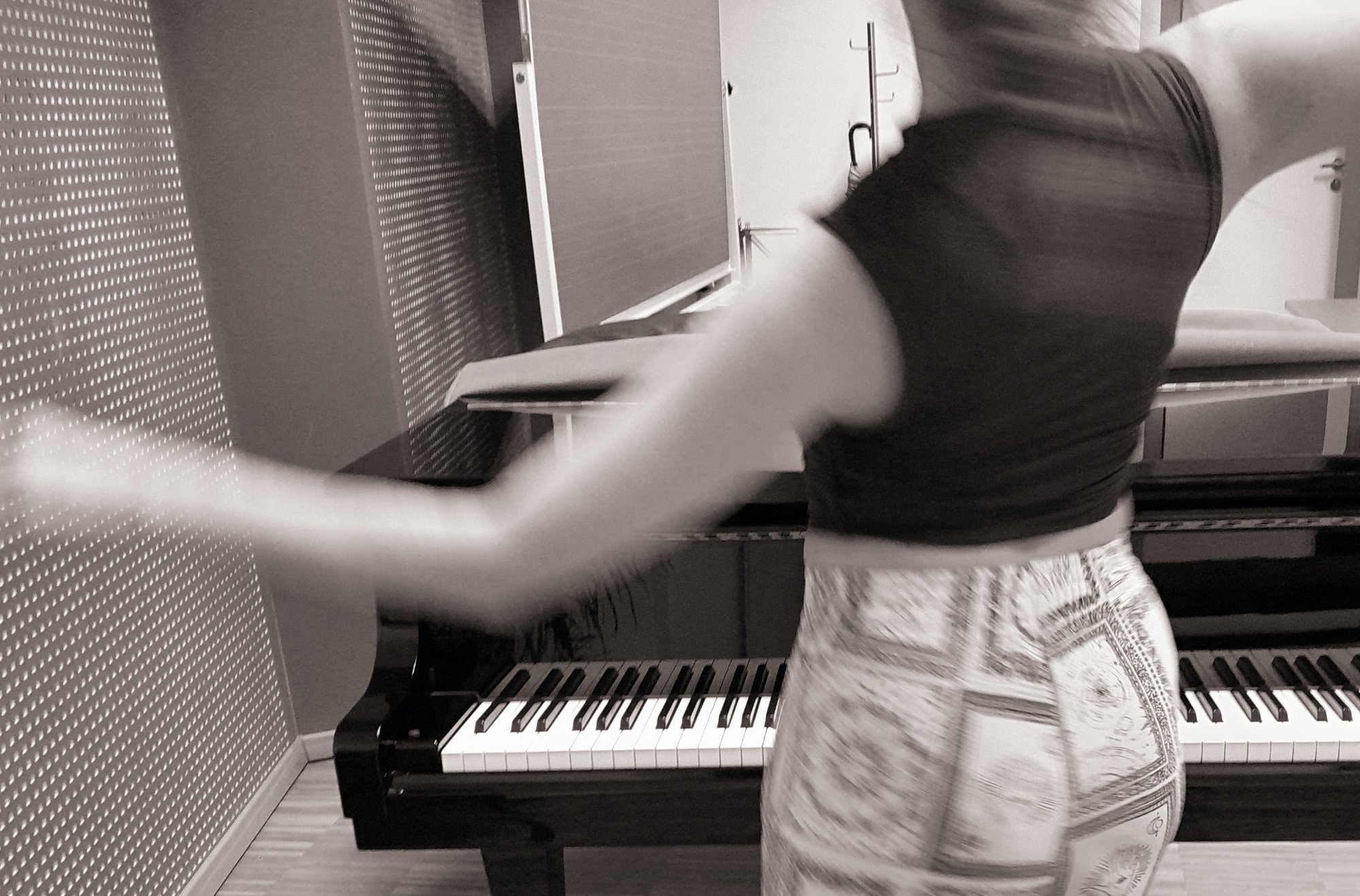 Schwarz/Weiß Motiv einer Frau, die vor einem Klavier tanzt