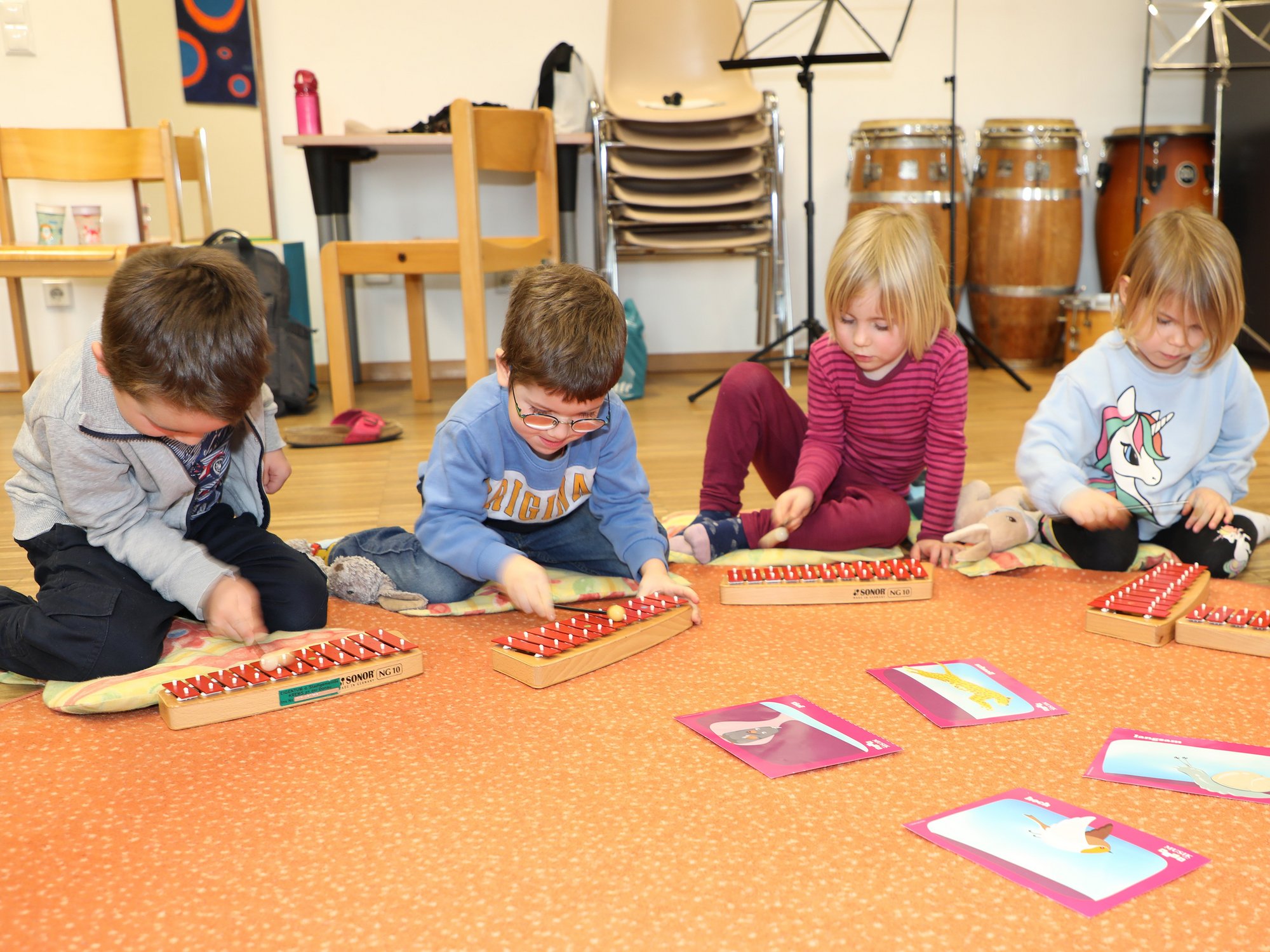 Vier kleine KInder spielen Xylophon