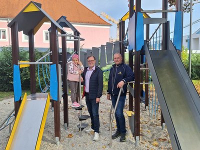 Am Spielplatz beim Klettergerüst ein Kind und zwei Herrn der Stadt Krems