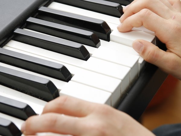 Zwei Hände spielen auf einer Klaviertastatur