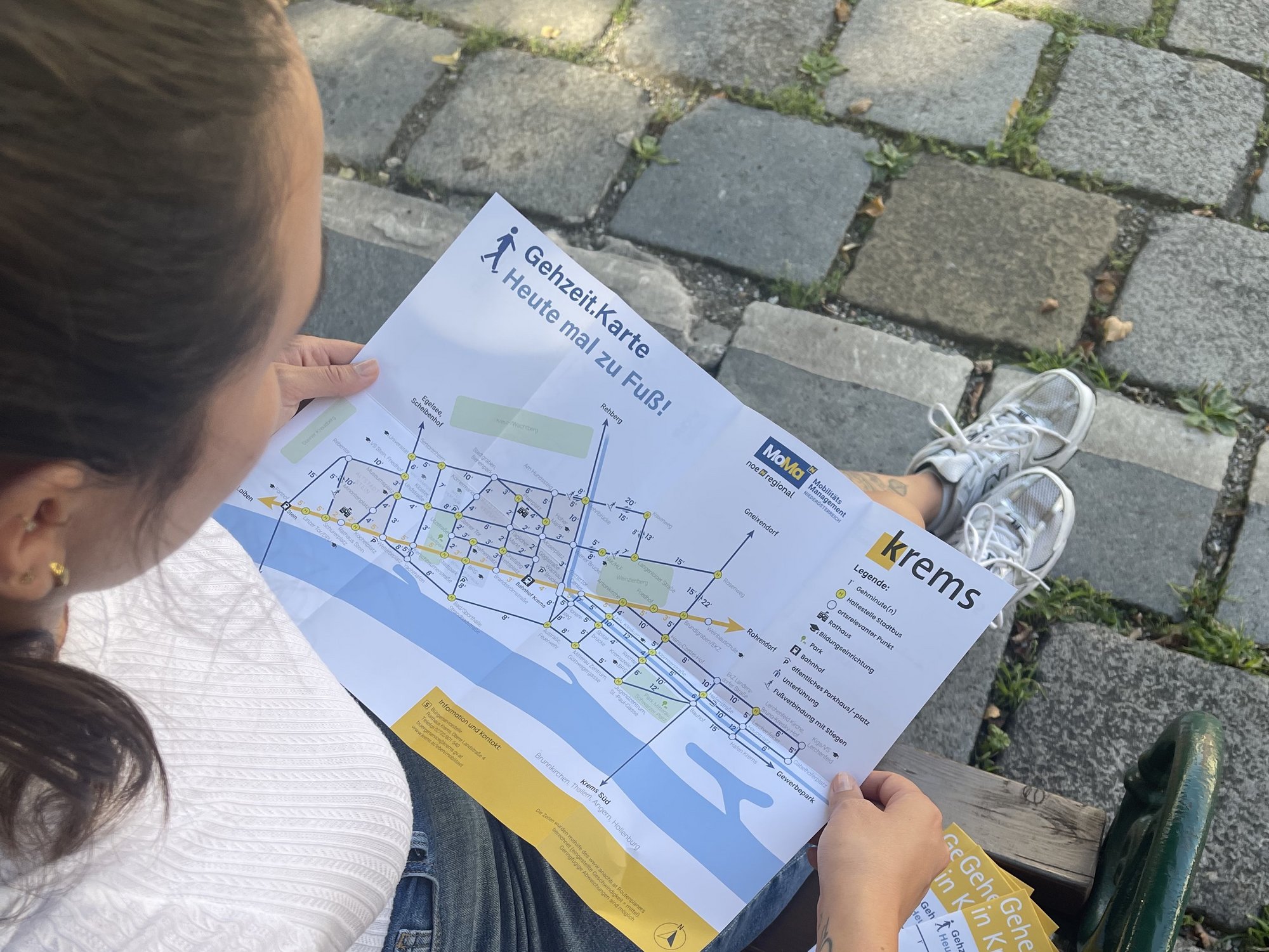 Junge Frau auf einer Parkbank studiert die neue Gehzeit.Karte