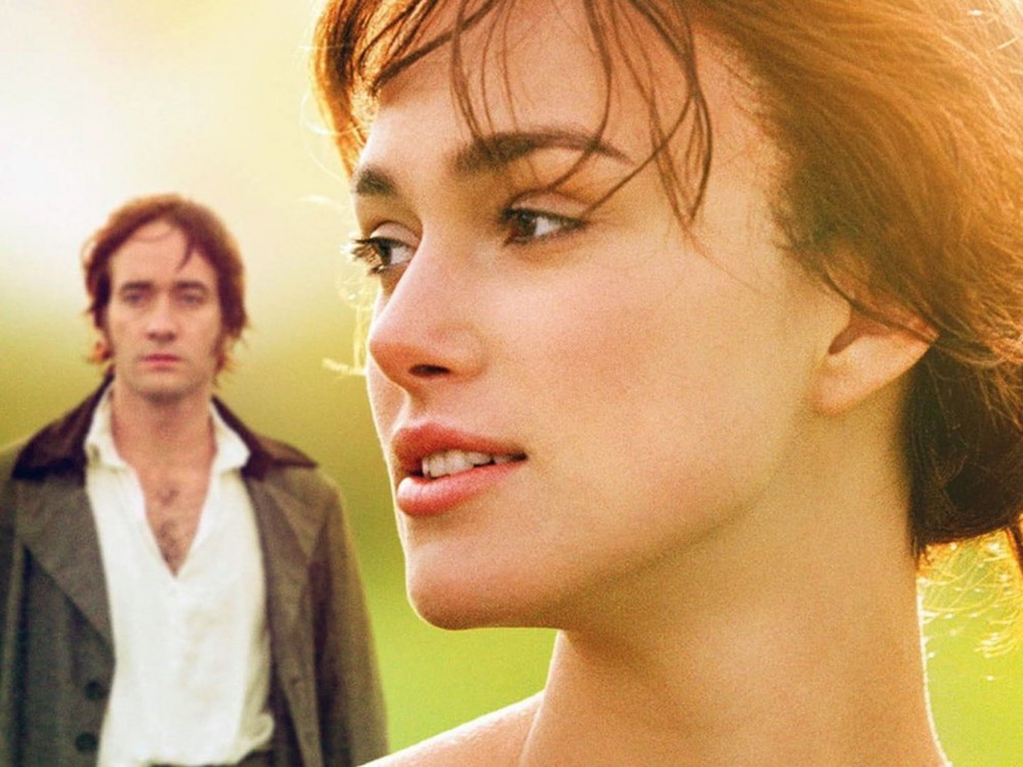 Filmszene: Nahaufnahme einer Frau mit Blick in die Ferne, im Hintergrund ein Mann auf einer Wiese.