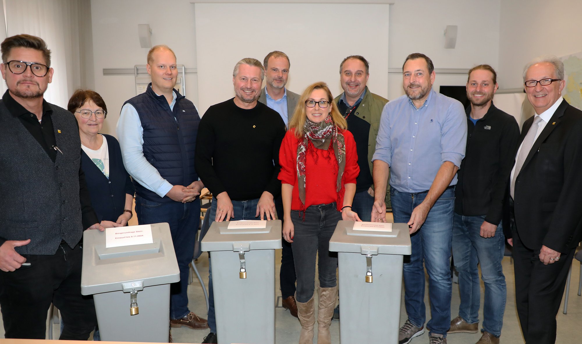 Gruppenfoto von Politikern und Rathausmitarbeitern mit drei Wahlurnen