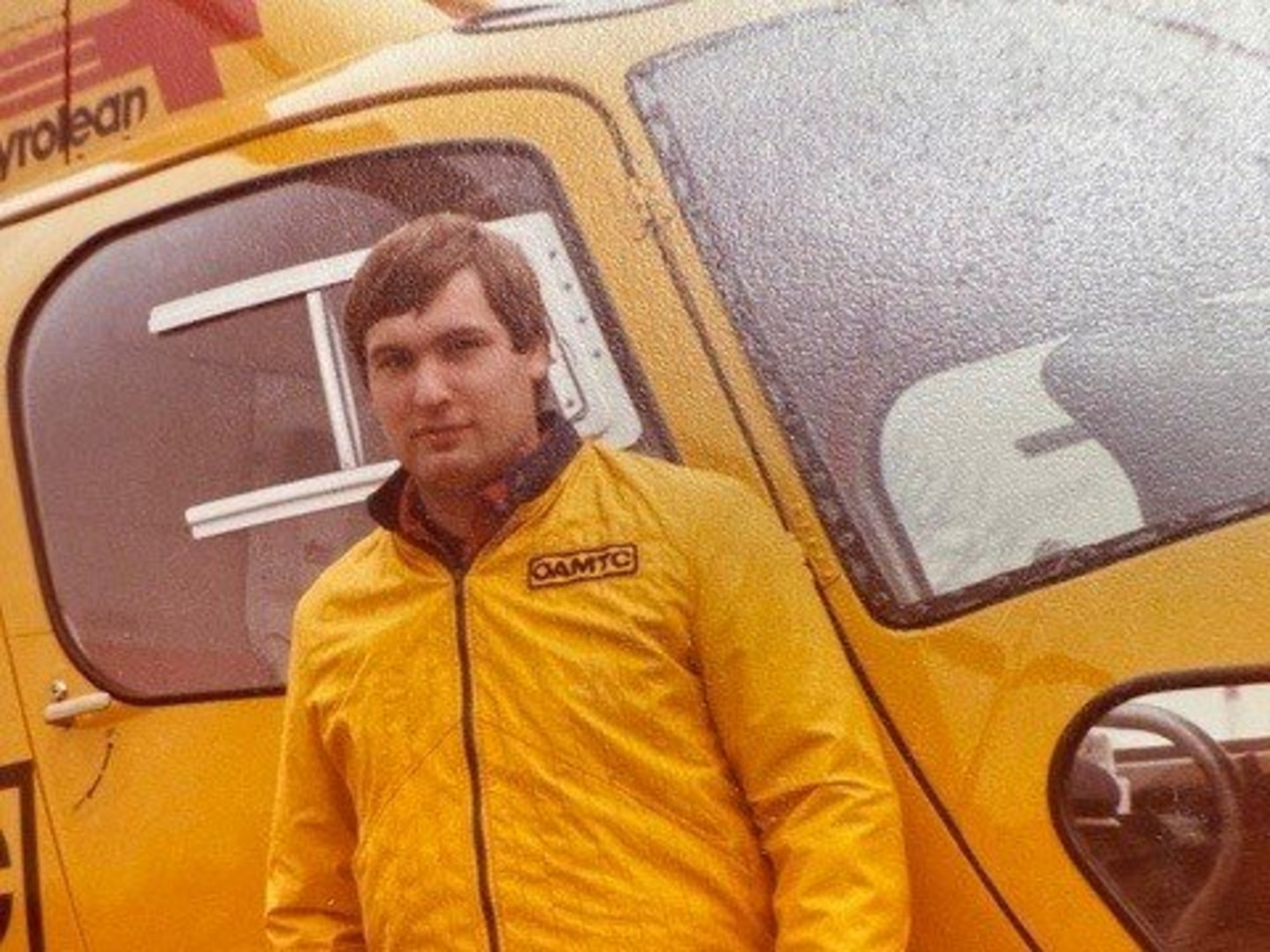 Mann in ÖAMTC-Einsatzkleidung vor einem gelben Notarzthubschrauber.