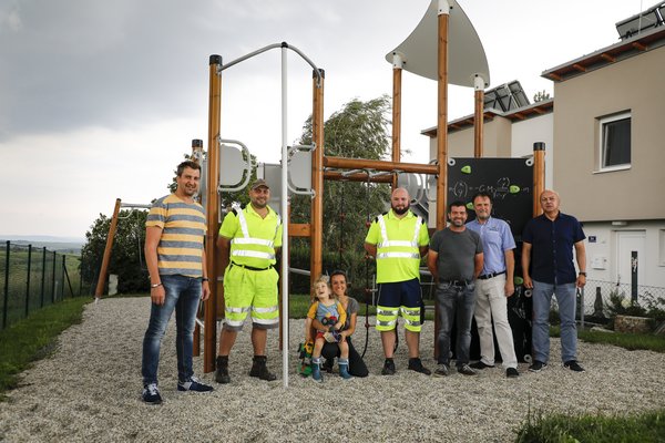 Lokalaugenschein auf dem neuen Spielplatz in Egelsee: Wirtschaftshof-Leiter Jürgen Stundner, die Stadtgärtner Patrick Strobl, Markus Edlinger und Paul Mistelbauer, Stadtrat Werner Stöberl und Bereichsleiter Mag. Roland Dewisch (von links) mit Emil und seiner Mutter