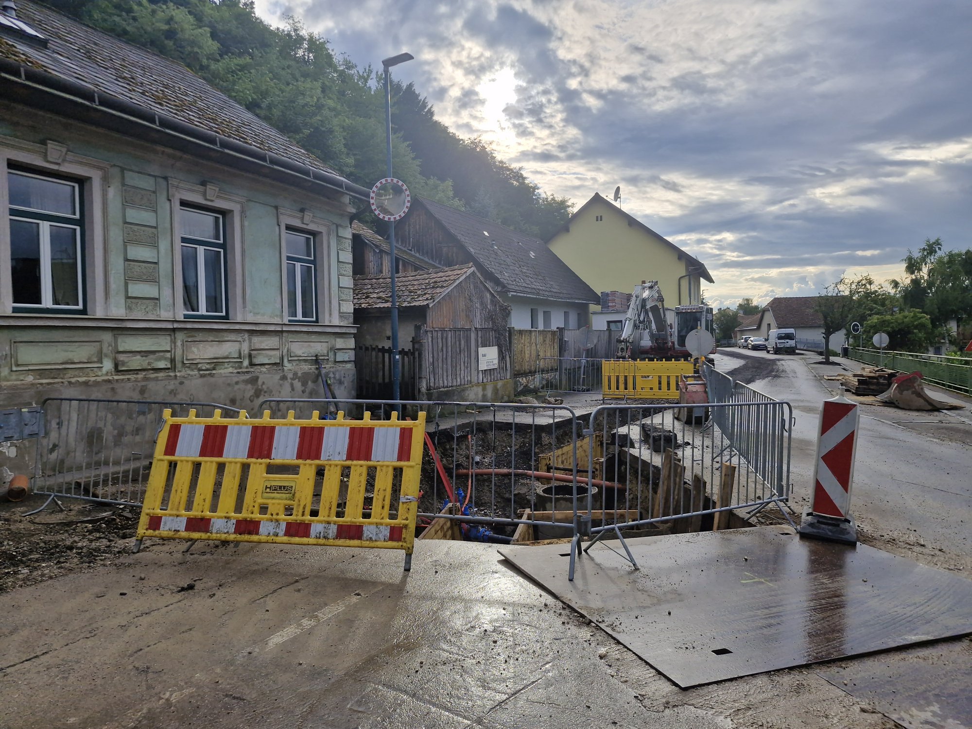 ChatGPT: Straßenbaustelle mit Absperrungen und Bagger in einem Wohngebiet.