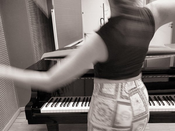 Junge Fraub tanzt vor Klavier