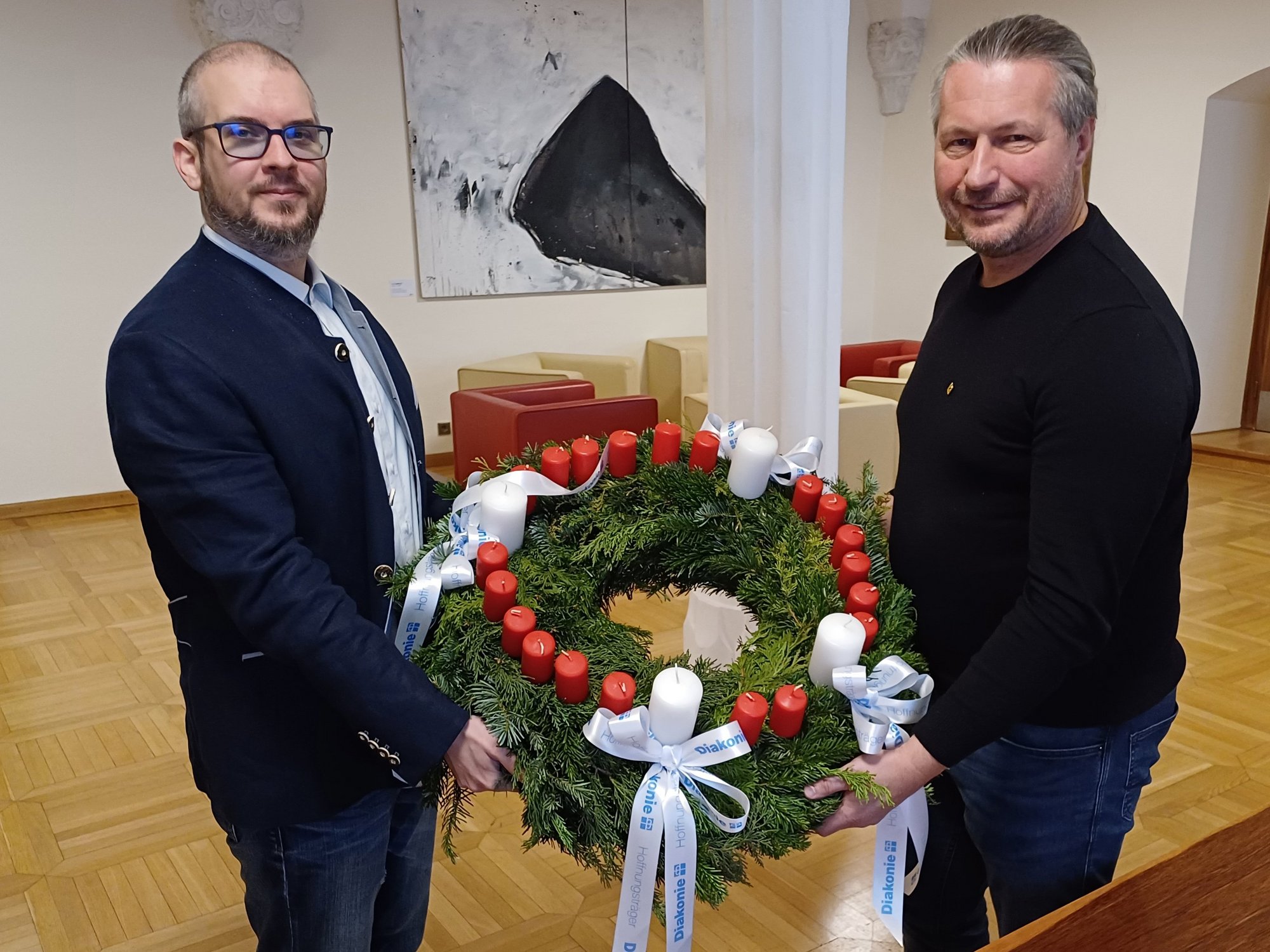 Pfarrer Jörg Kreil überreichte Bürgermeister Peter Molnar einen Adventkranz der Diakonie mit 24 Kerzen.