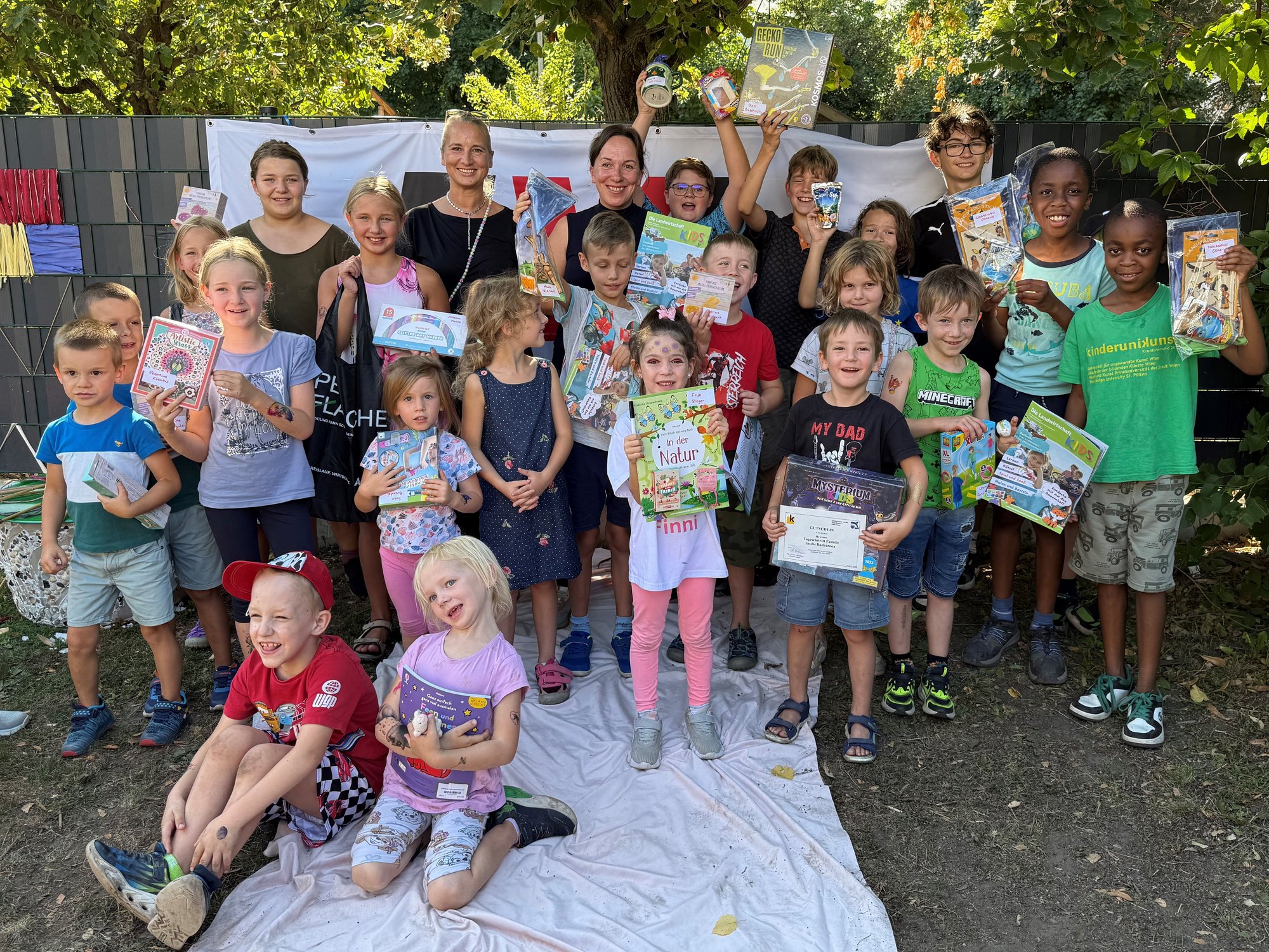 Alt-Texte sagte:  Gruppe von Kindern und Erwachsenen mit Büchern und Urkunden bei einer Veranstaltung im Freien.