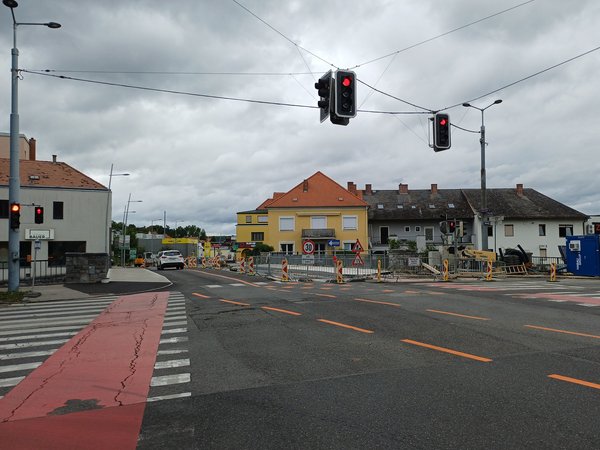 Blick auf die Wachaukreuzung in Krems mit Baustelle und roten Ampeln, im Hintergrund Wohnhäuser und Baustellenabsperrungen.